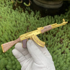 AK-47 Gold Arabesque miniature held in a gloved hand, showing its size
