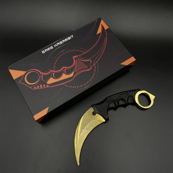 Karambit Lore trainer with its gold blade beside the gift box