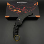 Karambit Lore trainer on its printed gift box, gold blade curving left